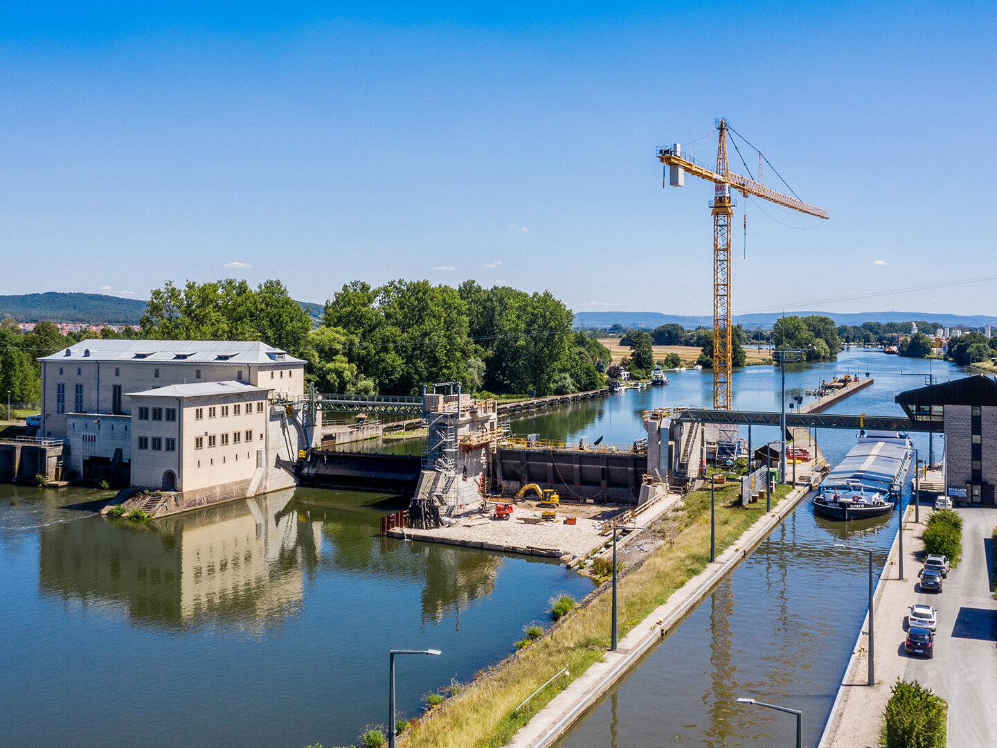 Wehranlage angrenzend an Bäumen und Kran im Hintergrund